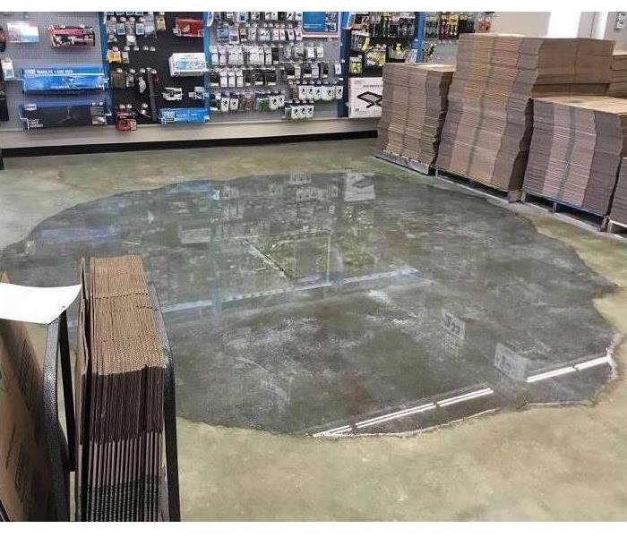 Large puddle on concrete floor of a retail space.